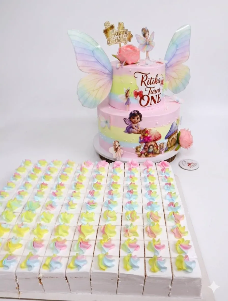 Two-tier fairy theme cake with butterfly wings and dessert boxes