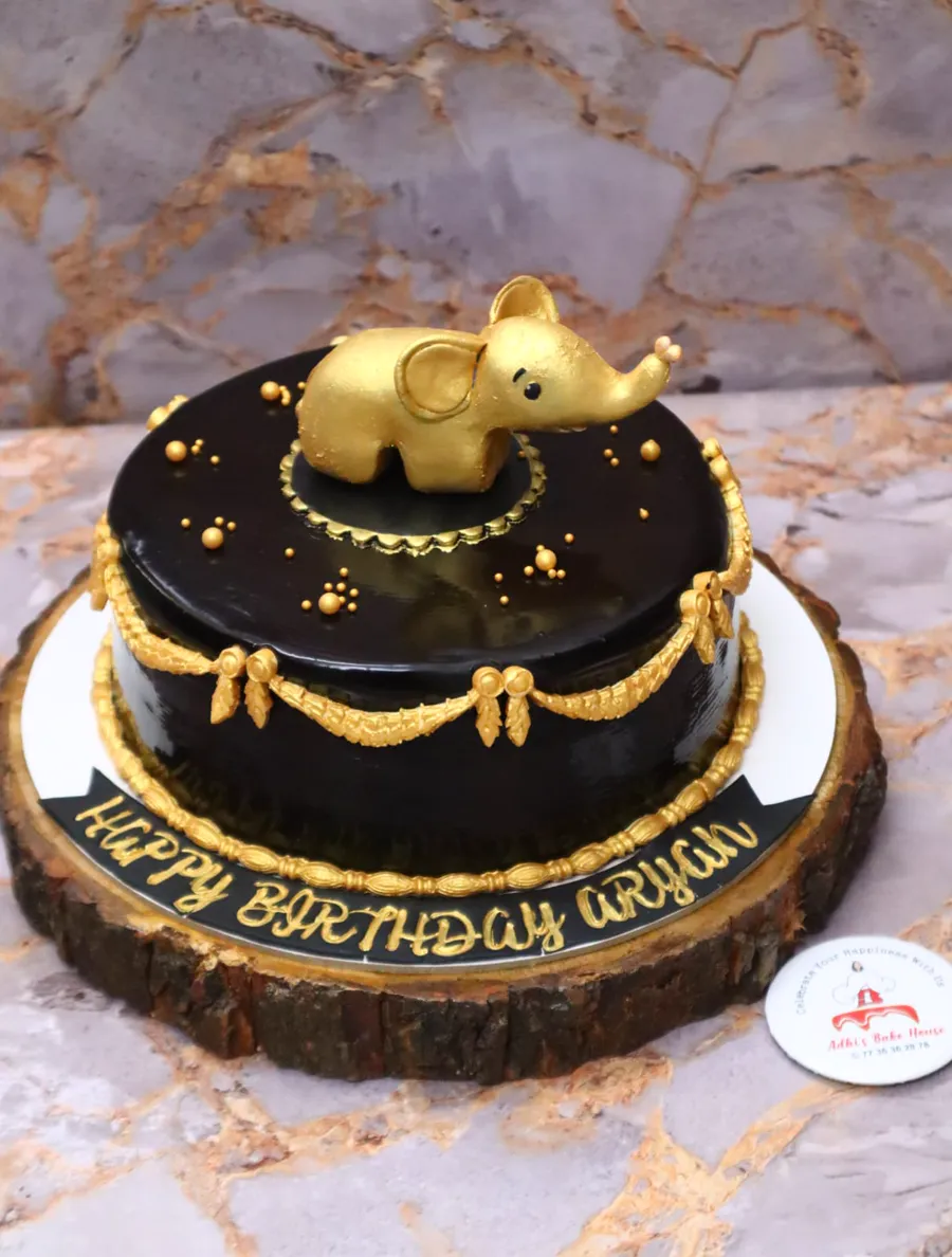 Chocolate birthday cake with a gold elephant and gold details