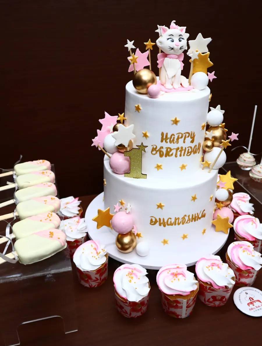 Two-tier kitty first birthday cake with a matching dessert table
