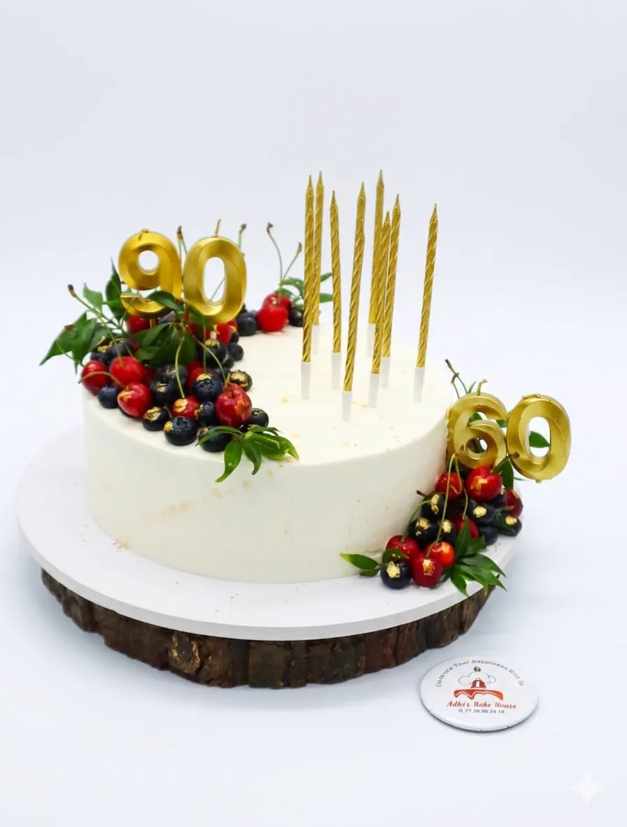 White 90th birthday cake with berries and gold candles