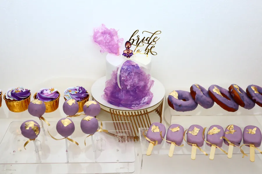 Purple dessert table with cupcakes, donuts and cake pops