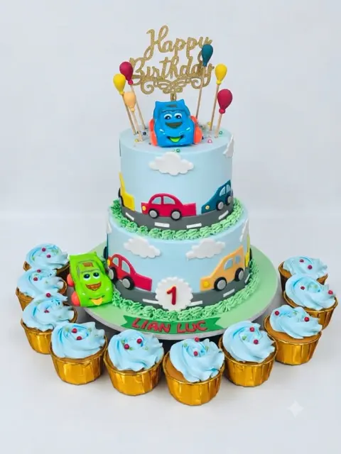 Two-tier car theme first birthday cake with matching cupcakes