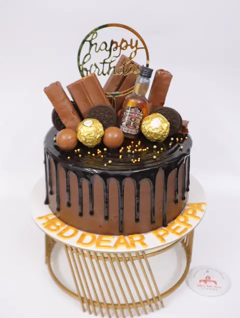 Chocolate drip cake loaded with chocolates on a gold stand