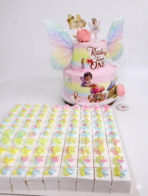 Two-tier fairy theme cake with butterfly wings and dessert boxes