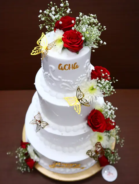 Three-tier white cake with red roses and gold butterflies