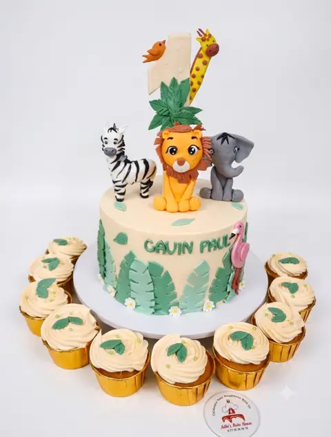 Jungle theme cake with lion, giraffe and zebra toppers and cupcakes